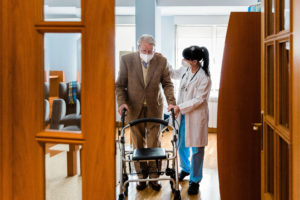 Nurse helping elderly man with a walker